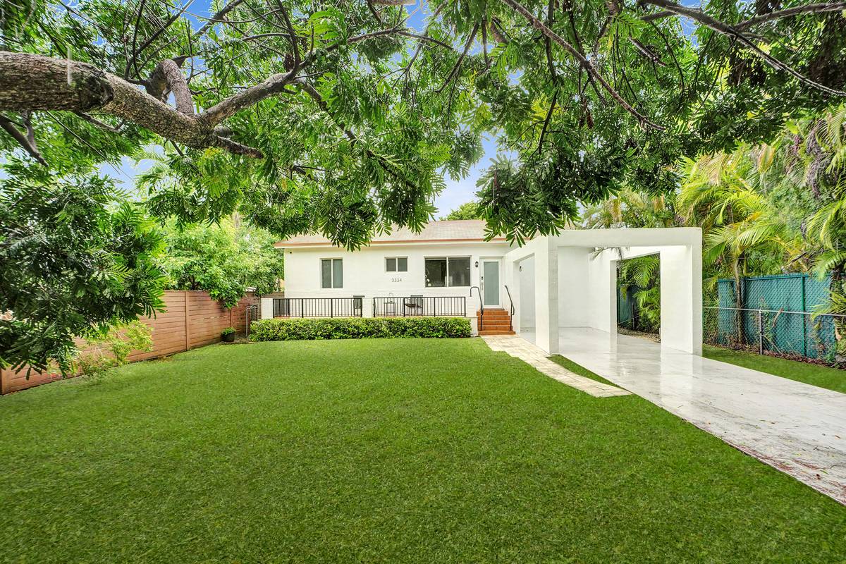 Front of 3334 SW 64th Ave in Coral Terrace with a wide lawn, front terrace and driveway under a shade tree