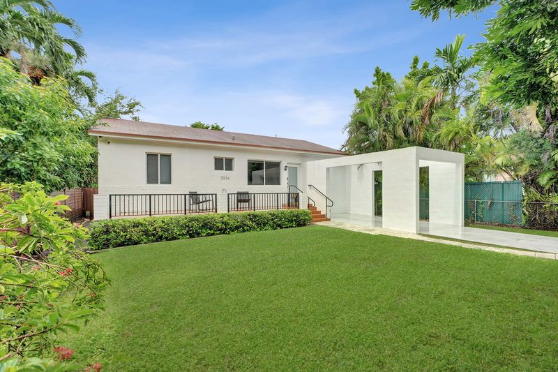 Front of the home with a railed terrace, hedge and lawn