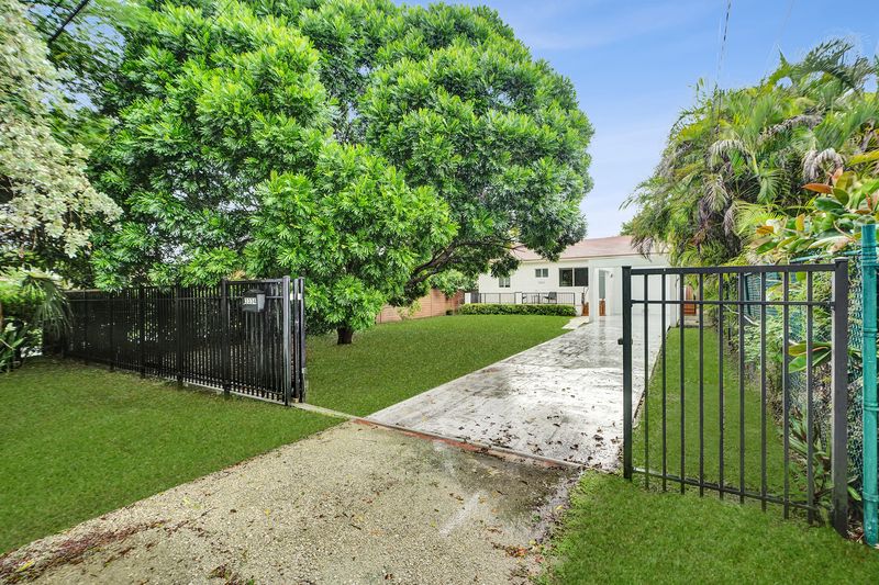 Driveway with a black metal gate, lawn and mature trees