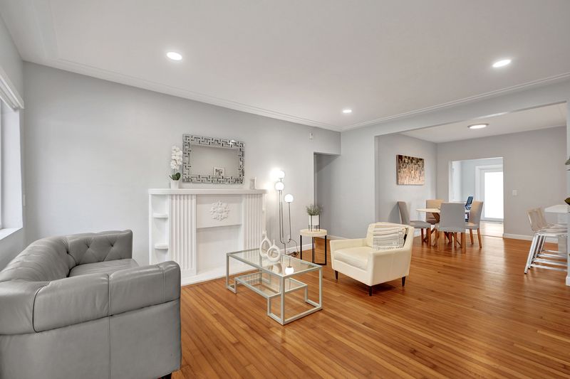 Living room with wood floors and recessed lighting, open to the dining area