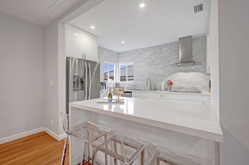 Renovated kitchen with white counters, stainless appliances and a breakfast bar