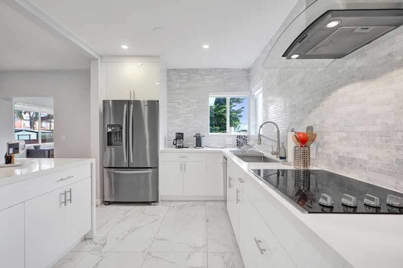 Kitchen with a stainless refrigerator, cooktop and stone backsplash