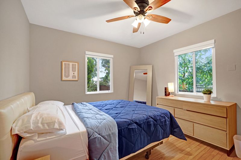 Second bedroom with wood floors, two windows and a ceiling fan