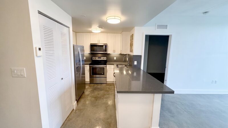 Apartment kitchen with stainless appliances and concrete floors at 4332 W Flagler Street