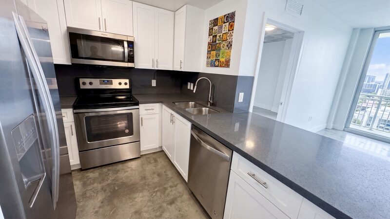 Kitchen with stainless range and white cabinetry in a unit at 4332 W Flagler Street