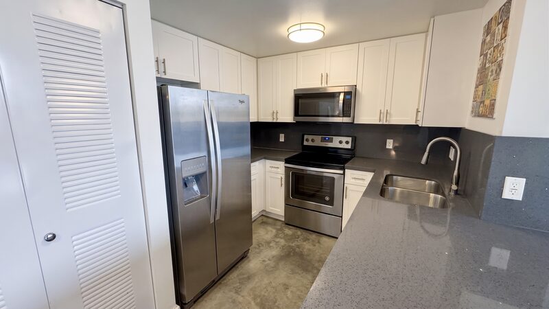 Kitchen with stainless refrigerator and dark counters in a unit at 4332 W Flagler Street