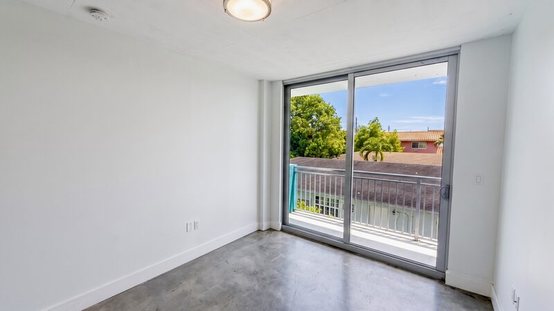 Living area with floor-to-ceiling impact glass opening to a private balcony at 4332 W Flagler Street