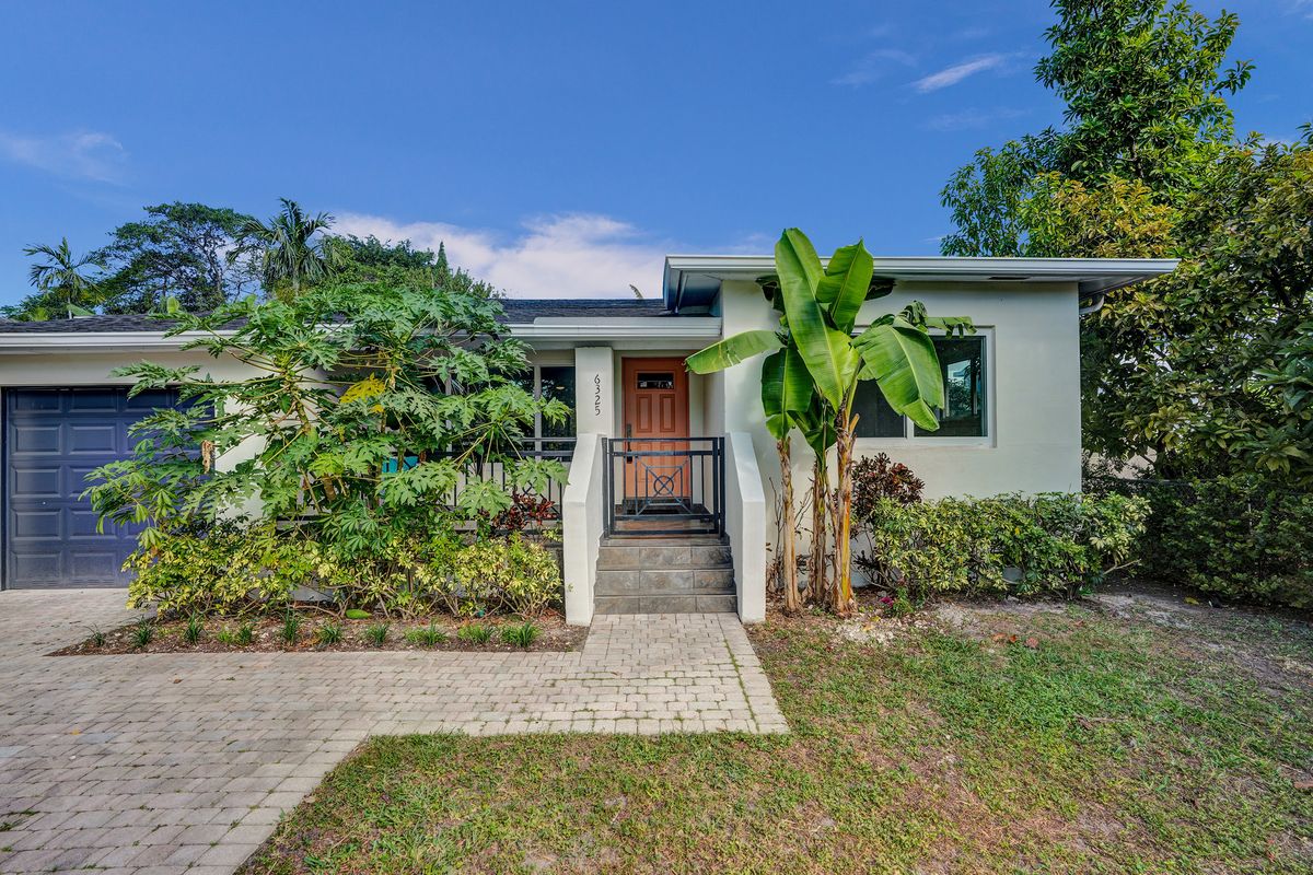 Front of 6325 SW 30th St in Coral Villas with a paver driveway, garage and tropical landscaping