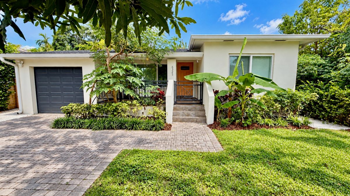 Front of 6325 SW 30th St in Coral Villas with a paver driveway, garage and tropical landscaping