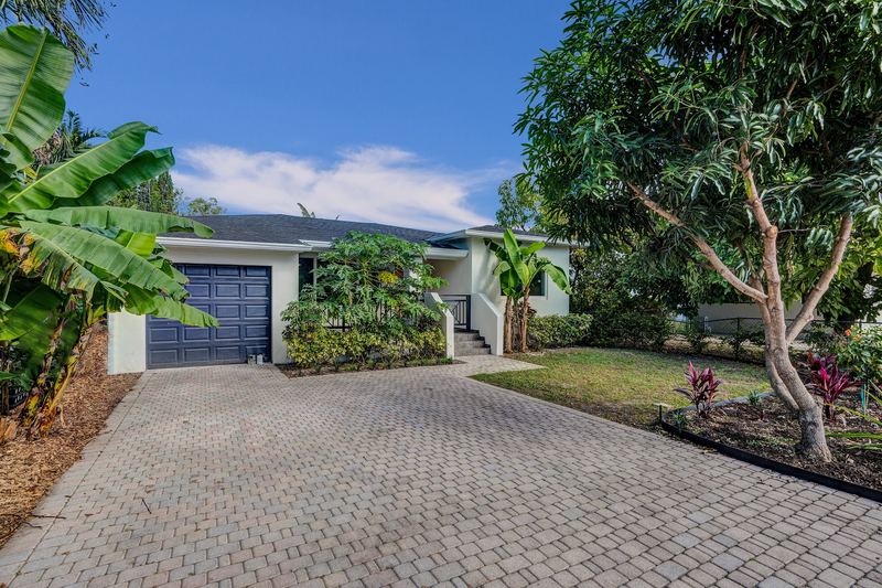 Paver driveway leading to the garage, with a shade tree and lawn