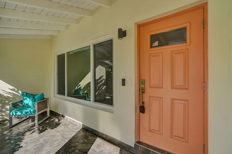 Covered front porch with a coral front door