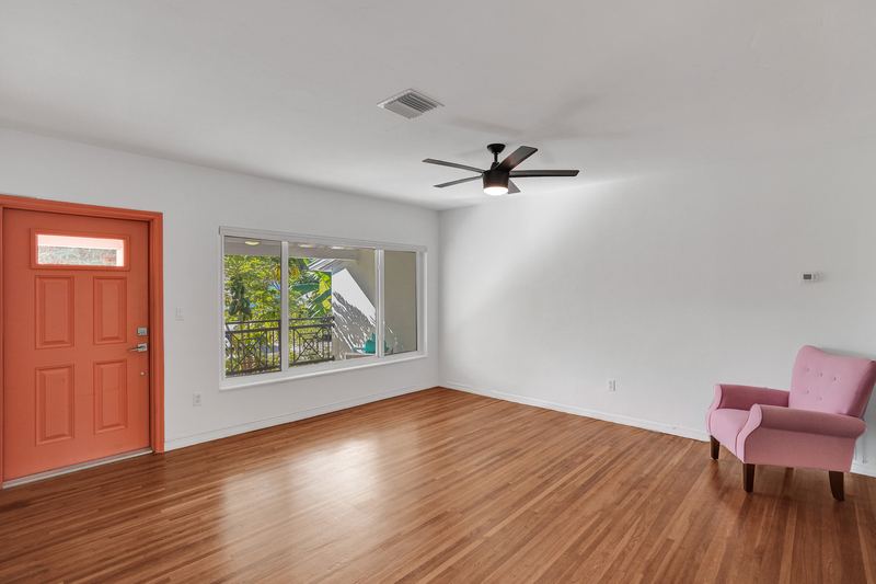 Living room with wood floors, a ceiling fan and the front door