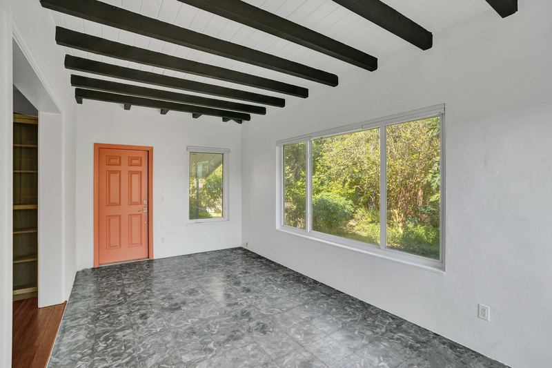 Back room with a beamed ceiling and a door to the patio