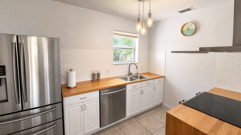 Kitchen with stainless dishwasher, butcher-block counter, and window over the sink at 8225 SW 44th Street, Miami