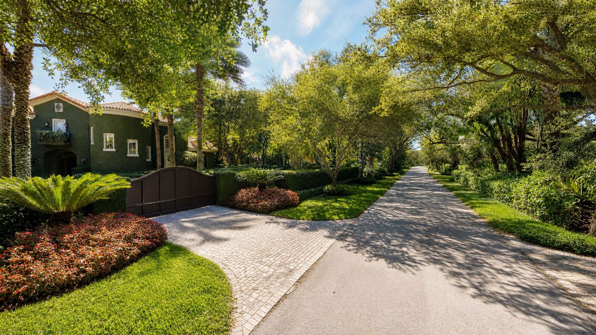 Oak-canopied residential street in Ponce-Davis, Miami, with an original mid-century home beside new estate construction.