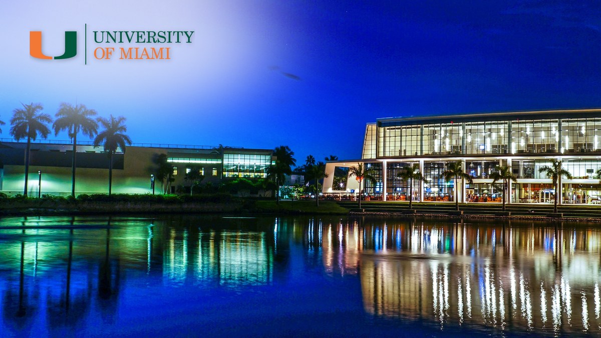 University of Miami Coral Gables campus at dusk reflected in the campus lake, with the UM logo.