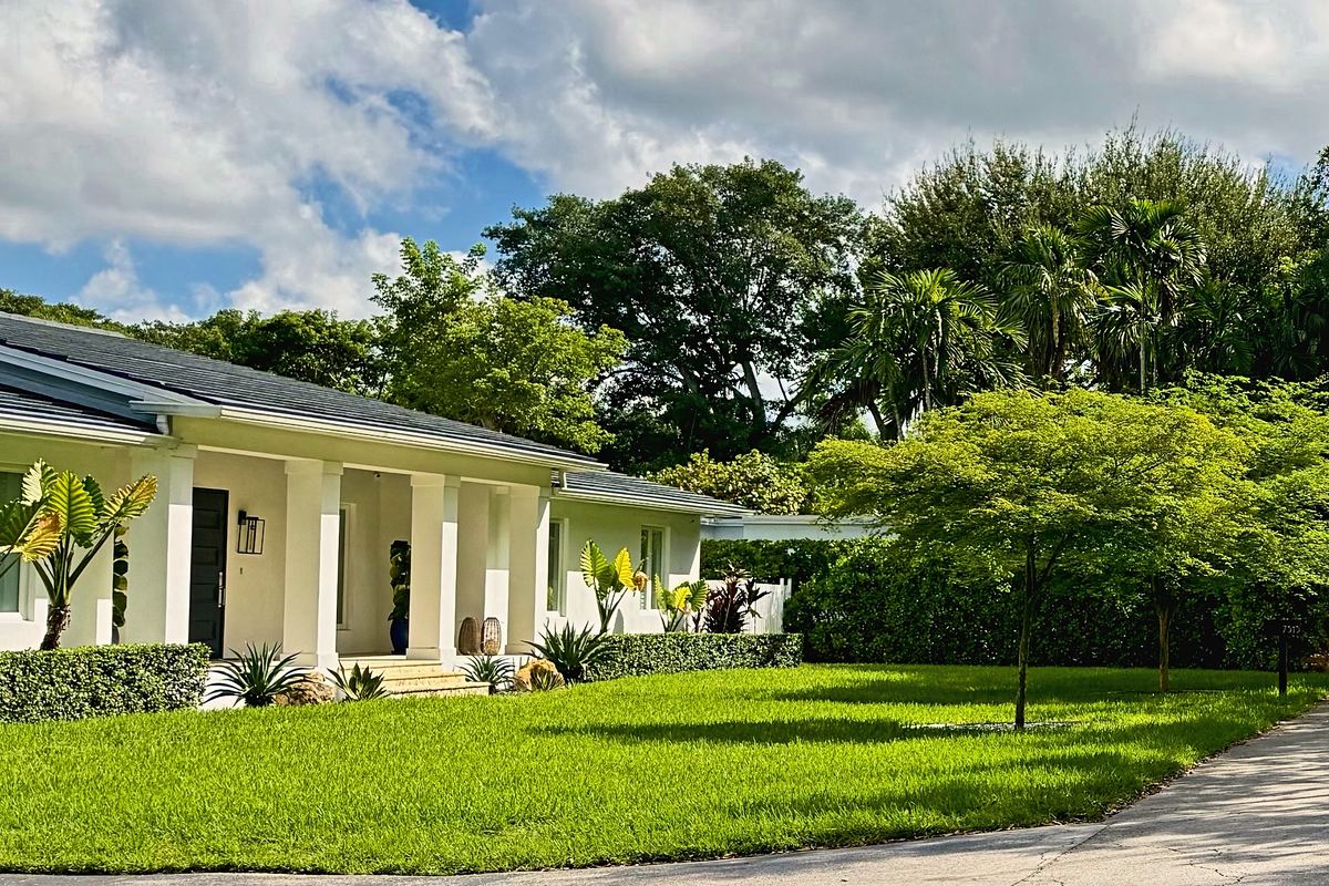 Single-story ranch home with a columned front porch and a deep front lawn under mature trees in Glenvar Heights